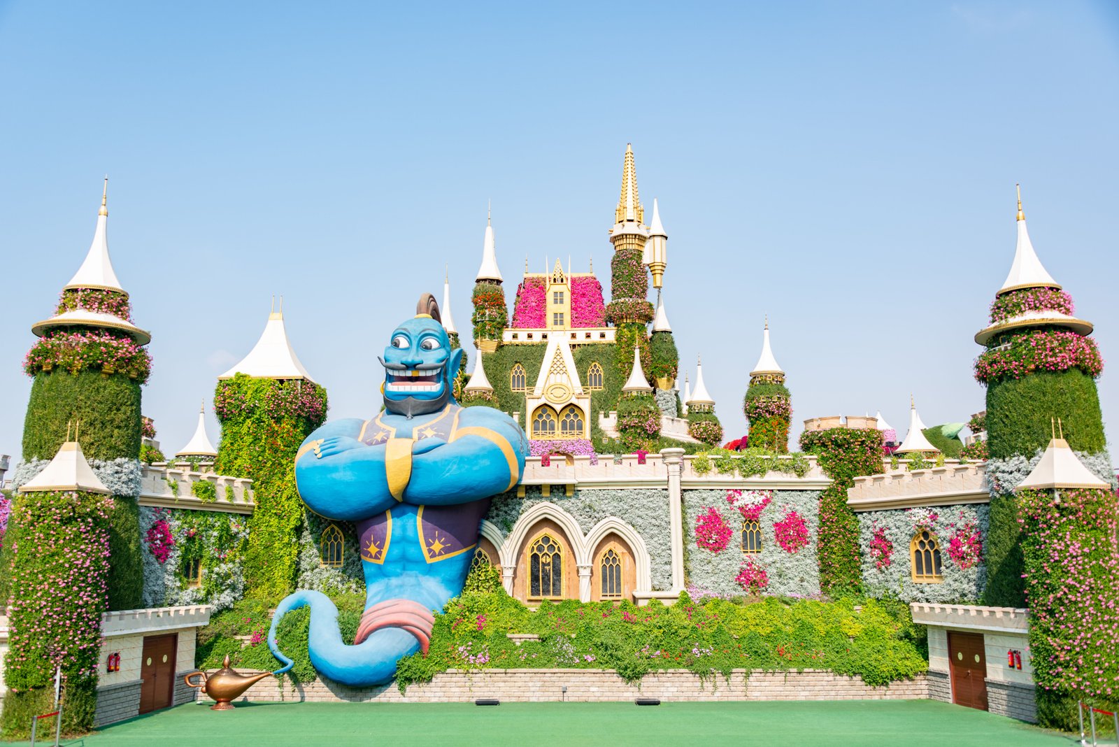 Charming floral castle with iconic genie statue in vibrant Dubai garden setting.