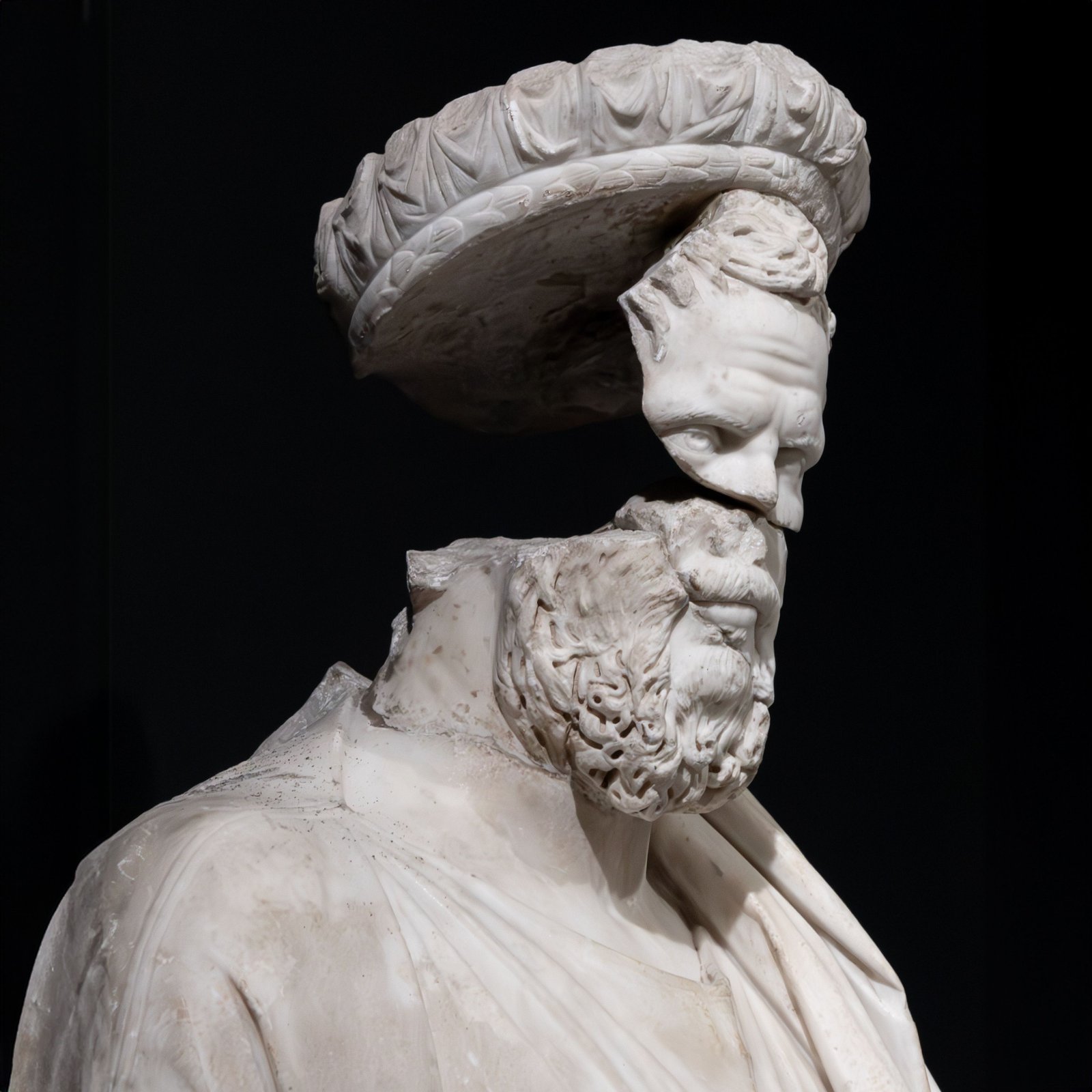 Close-up of a fragmented ancient marble sculpture with a detached headpiece.