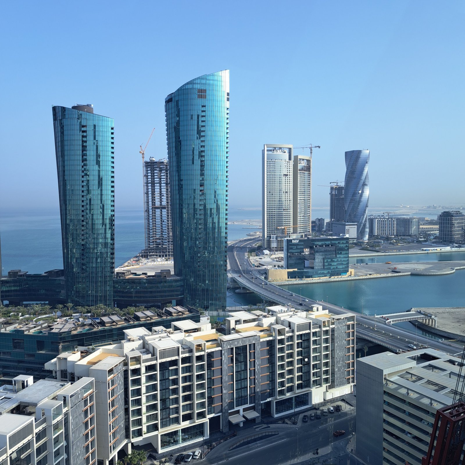 Captivating view of a modern skyline featuring waterfront skyscrapers under a clear blue sky.
