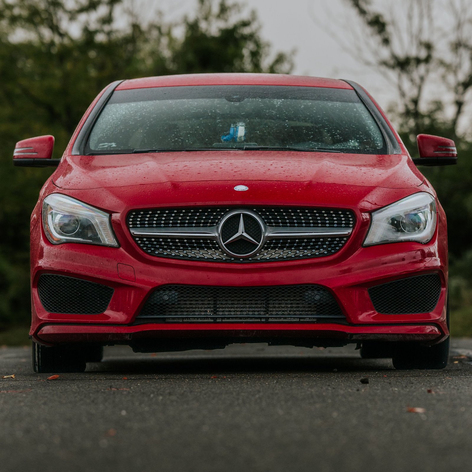 Front view of a red Mercedes-Benz on a wet surface, emphasizing elegance and luxury.