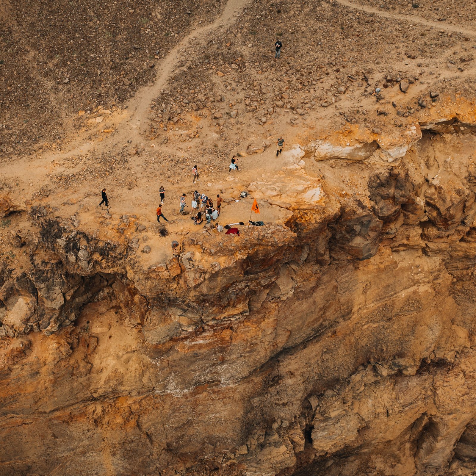 Aerial view of a group of people standing on a rocky cliff edge, offering a dramatic perspective.